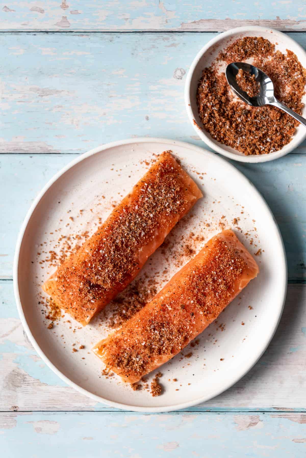 Adding seasoning to salmon fillets.