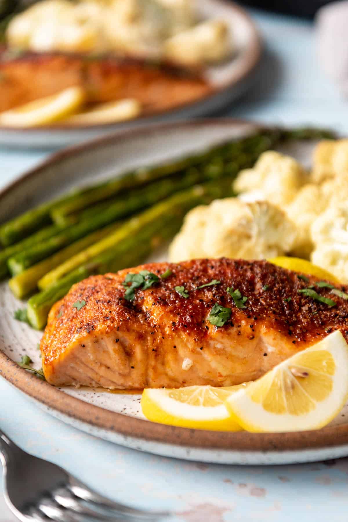 A 1-inch thick cooked salmon fillet on a plate with vegetables.