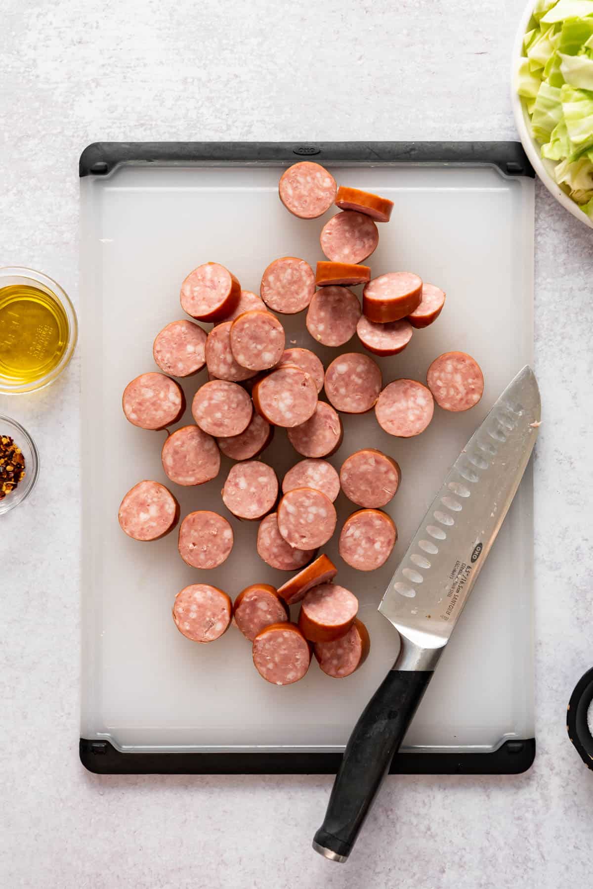Sliced polska kielbasa sausage on a cutting board with a knife.