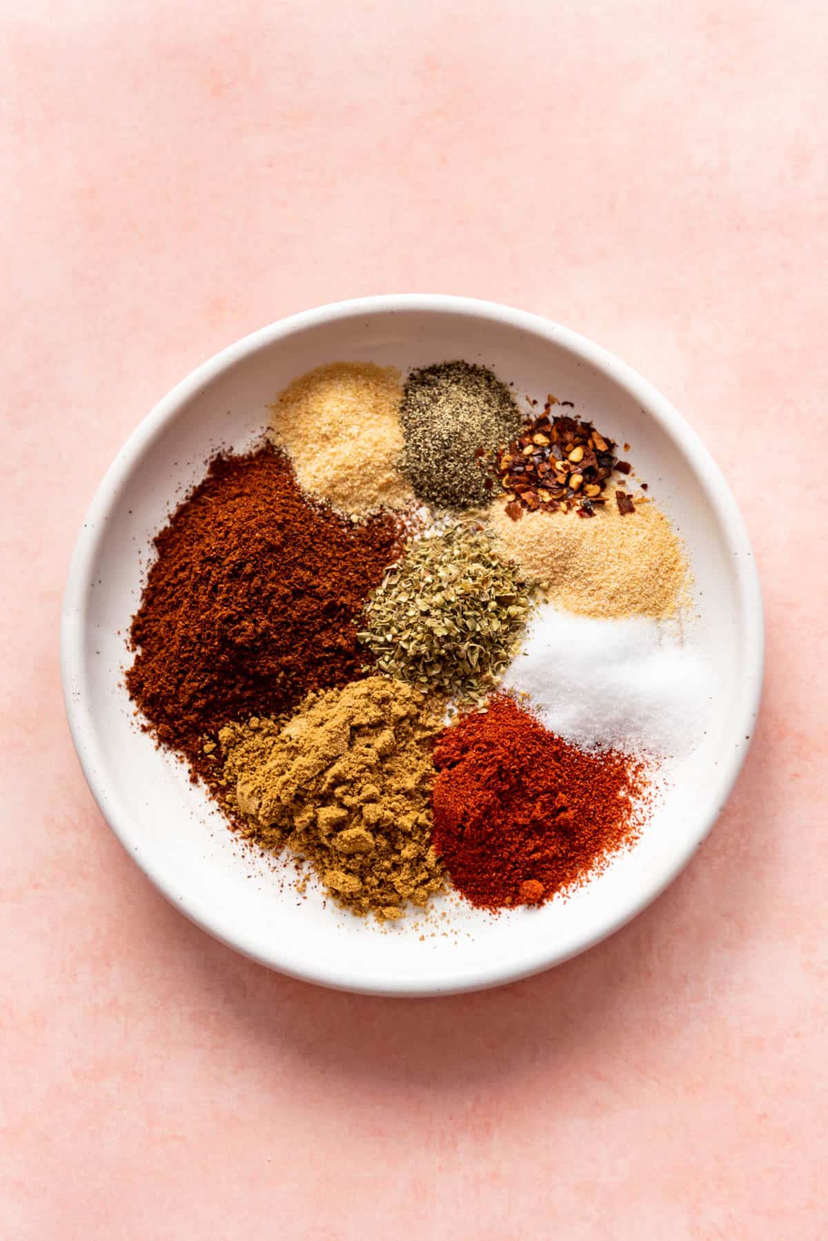 Spices in a taco seasoning recipe on a white plate.