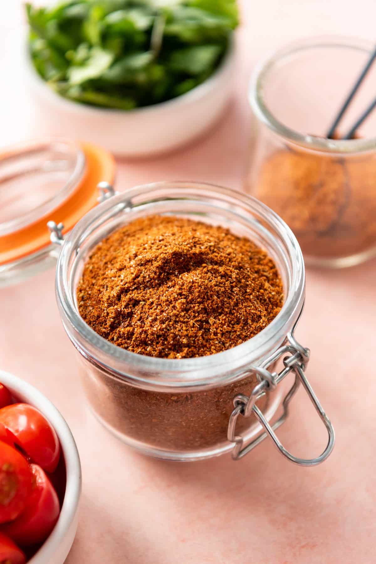 A glass jar with a lid filled with homemade taco seasoning.