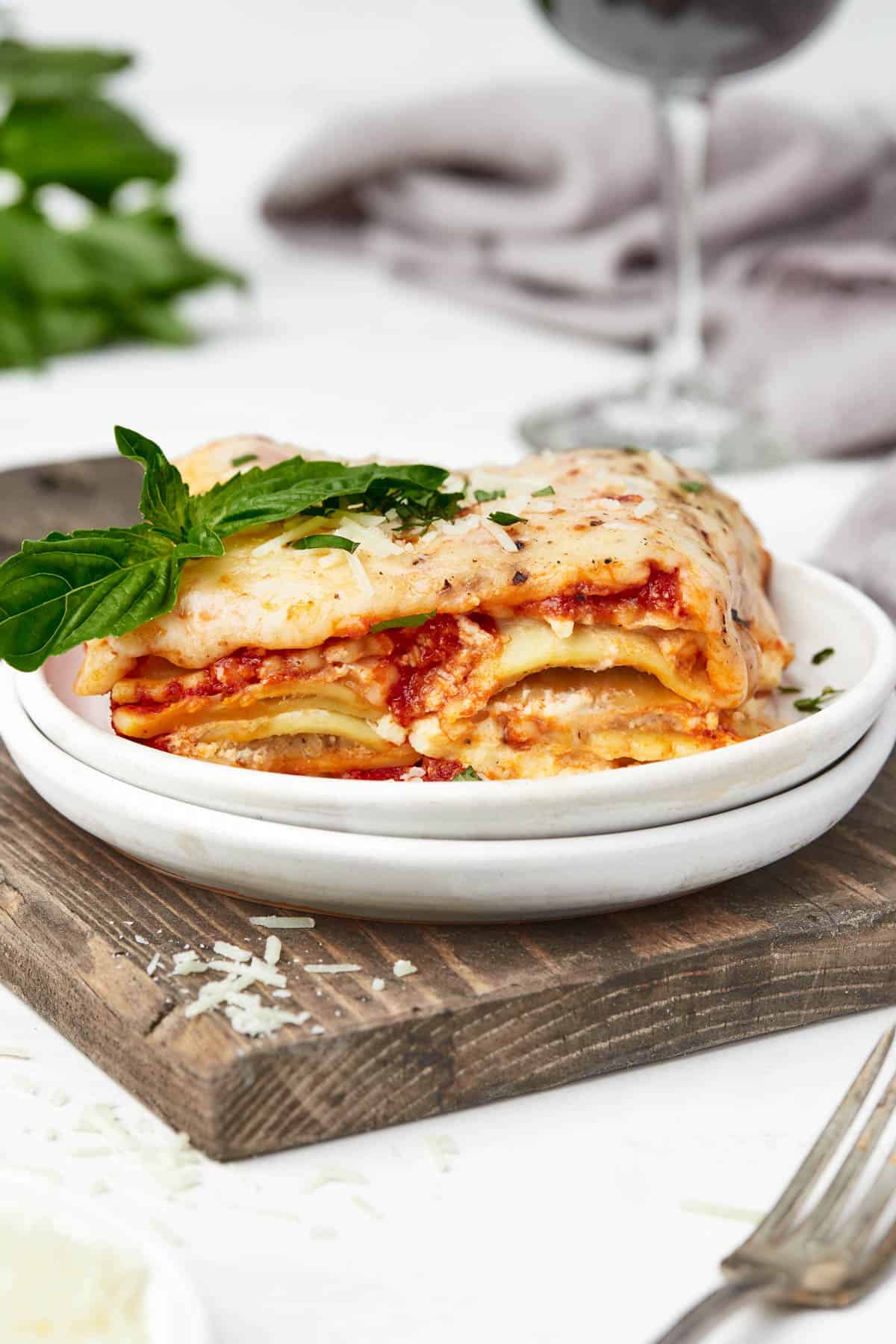A plate of ravioli lasagna on a wooden cutting board.