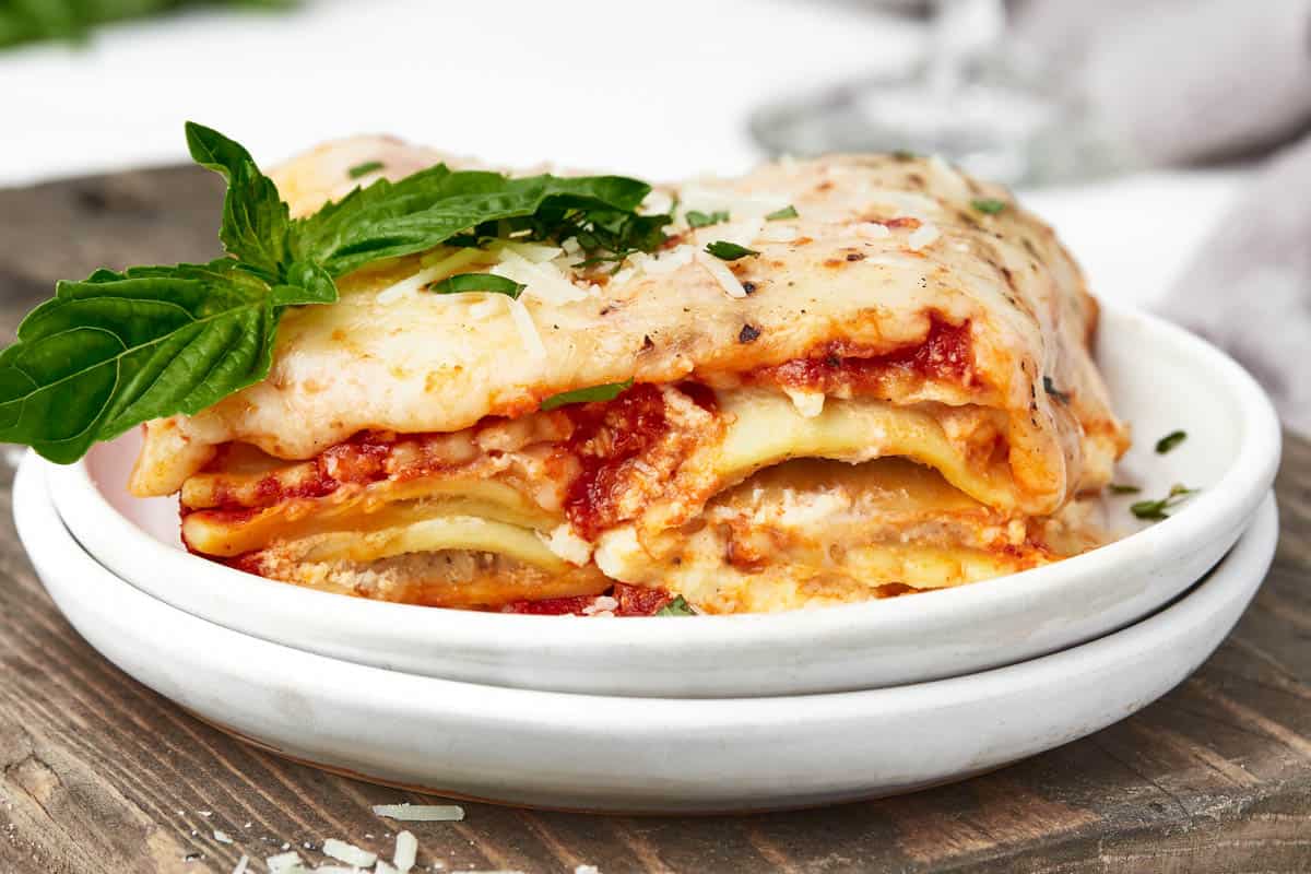 A side view of the layers of ravioli lasagna on white plates.