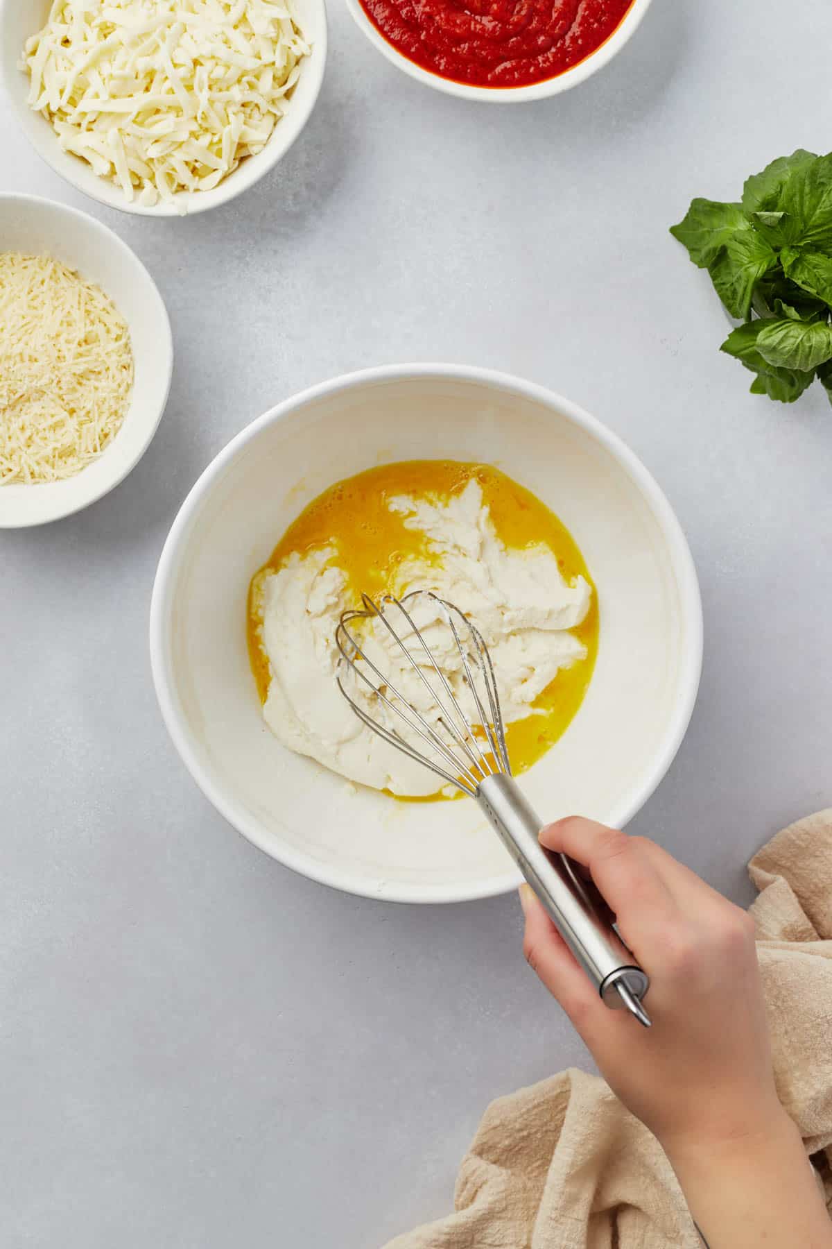 Whisking egg and ricotta cheese together in a bowl.