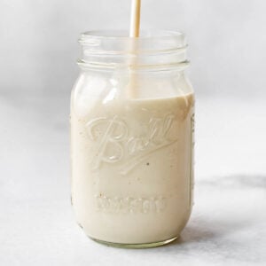 Homemade alfredo sauce being poured into a glass mason jar.