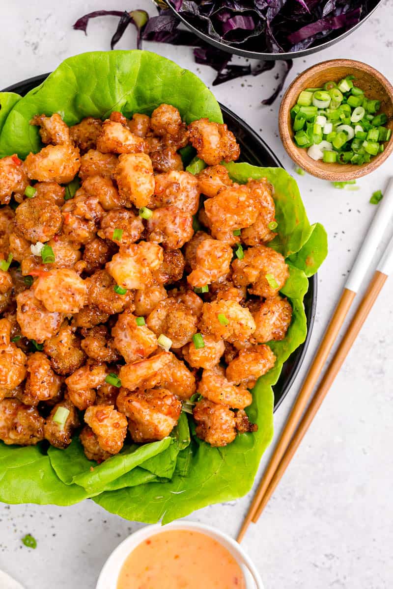 An overhead shot of bang bang shrimp in a large bowl with a pair of chopsticks beside it