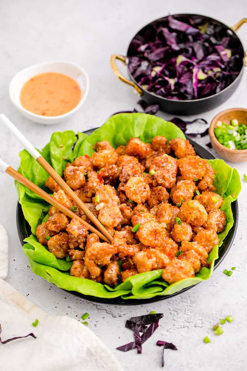Bang bang shrimp in a bowl with butter lettuce and a pair of chopsticks