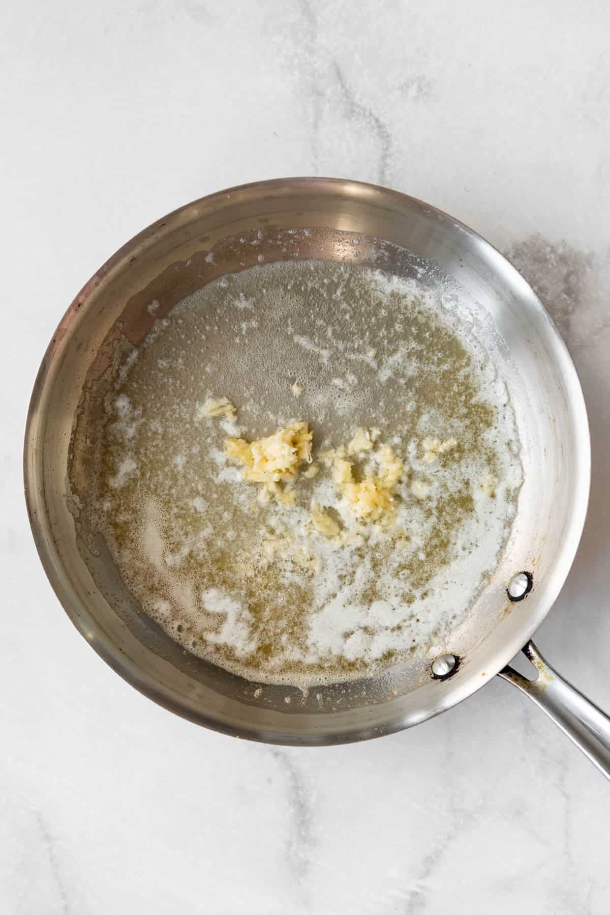 Sauteeing minced garlic in butter in a pan.