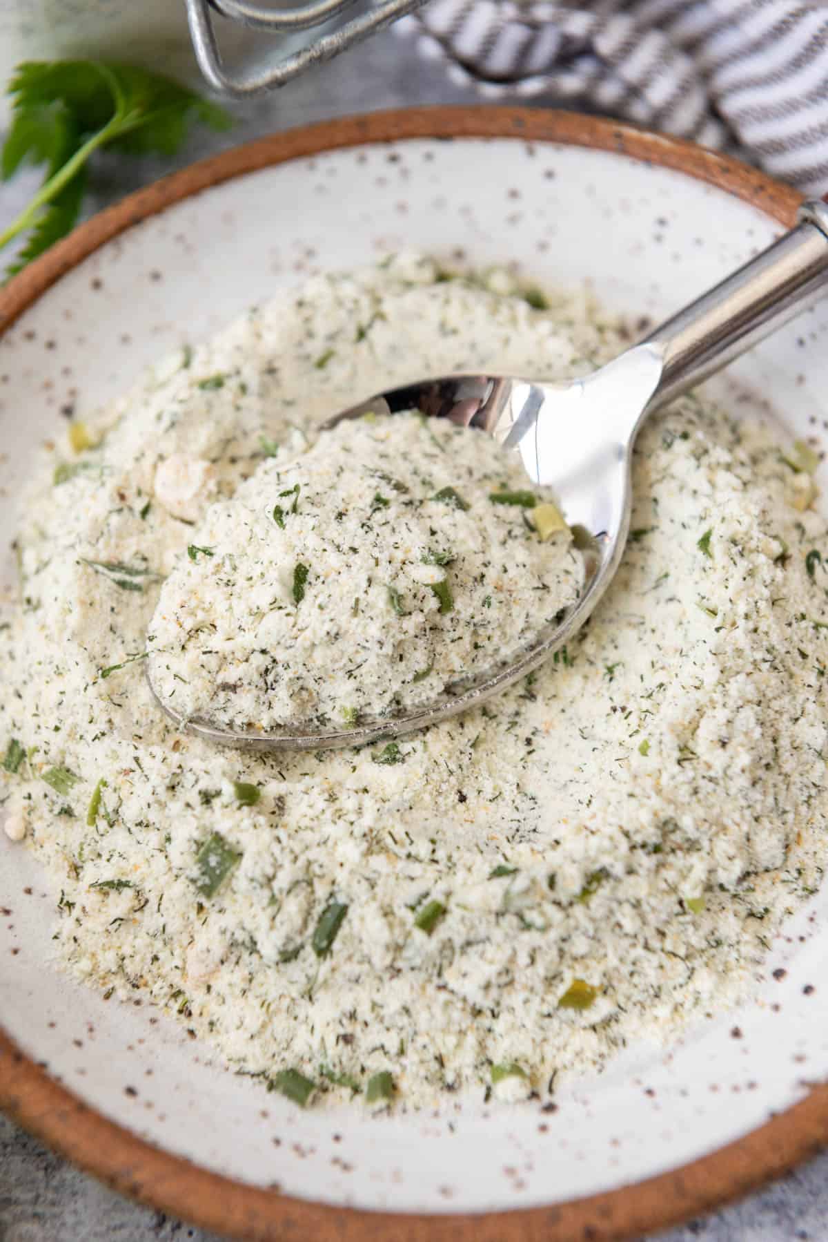 A small mound of homemade ranch seasoning made with powdered buttermilk on a plate with a spoon.