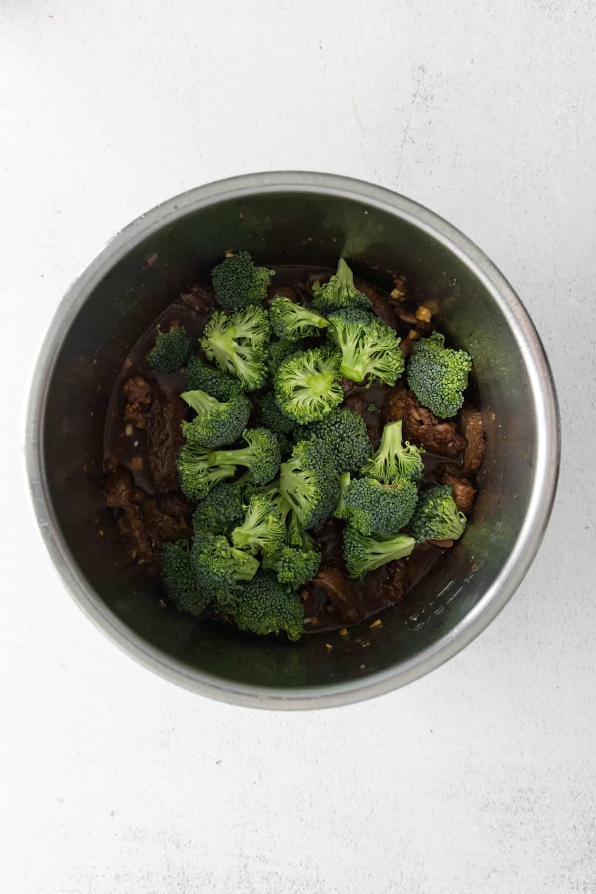 Adding broccoli to Mongolian beef made in the instant pot.