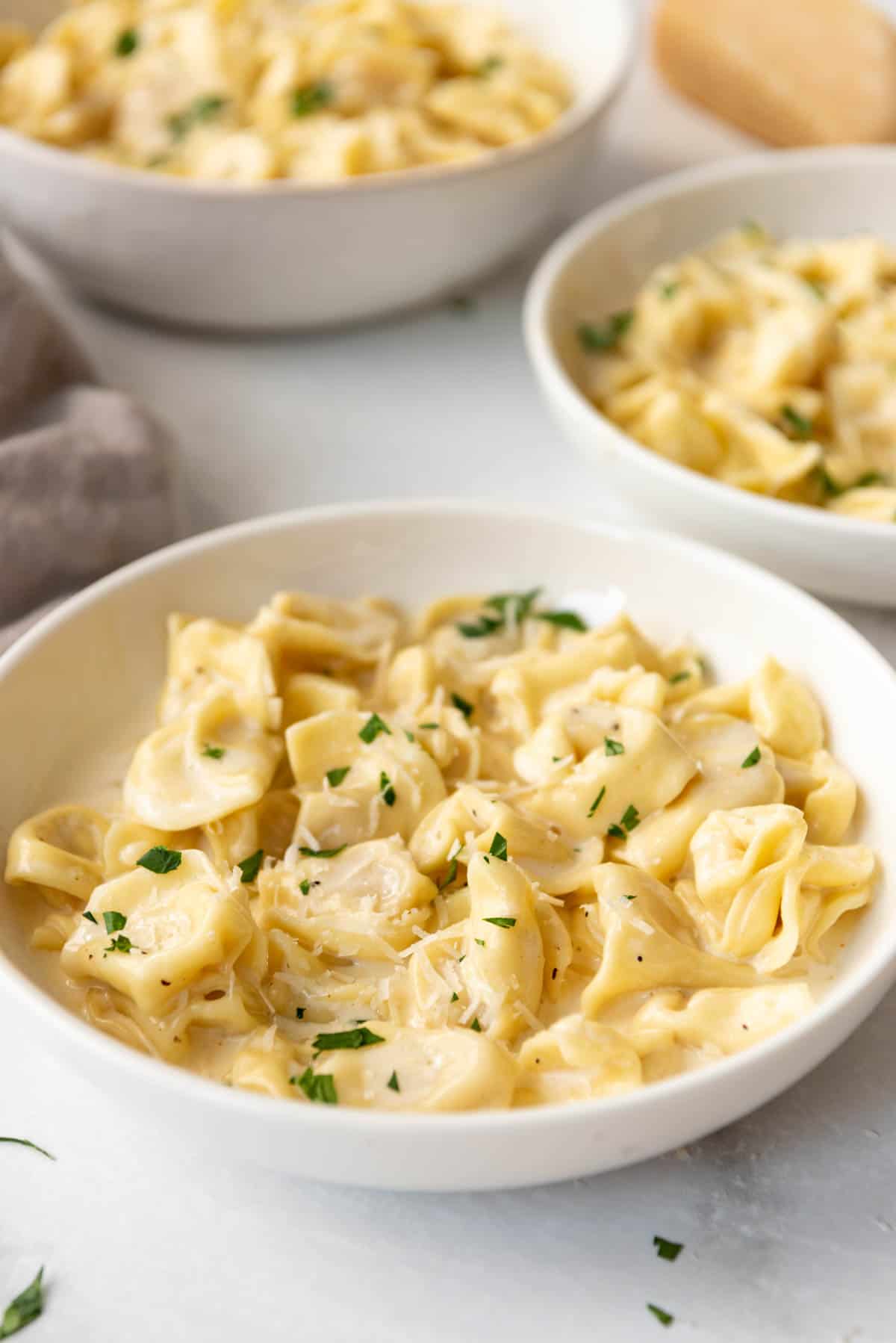 Bowls of tortellini alfredo pasta with parmesan cheese on top.