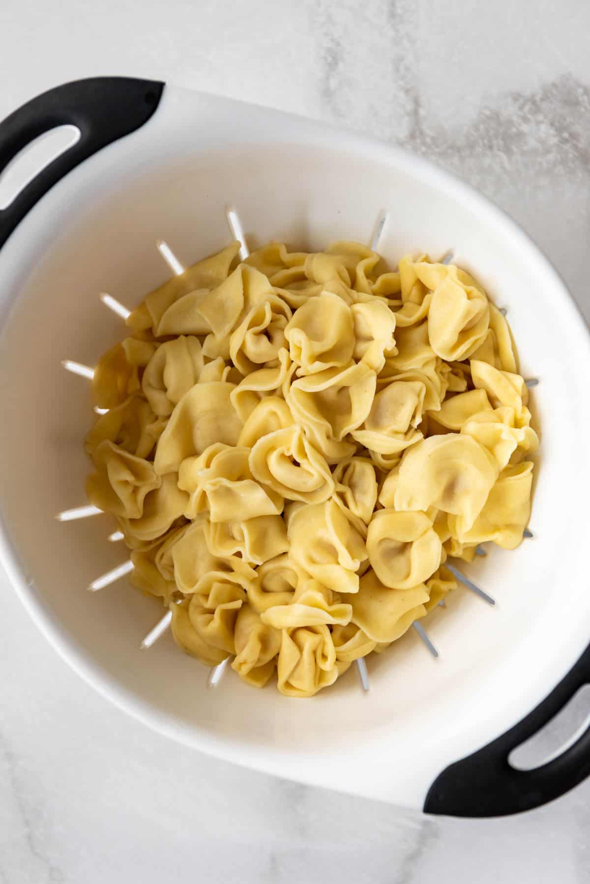 Cooked cheese tortellini pasta in a colander.