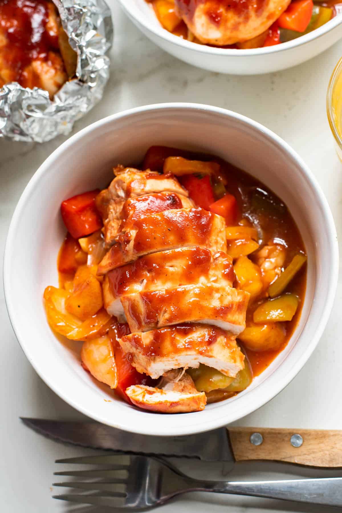 Sliced bbq chicken breast made in foil packets with pineapple and vegetables.