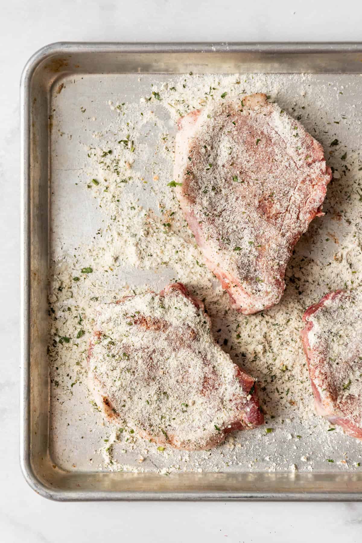Uncooked pork chops dredges in powdered ranch seasoning mix.