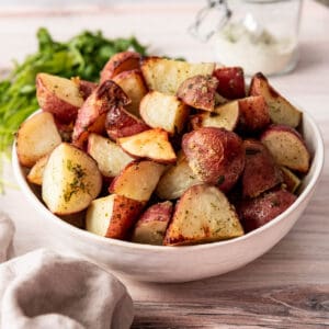 Ranch seasoned red potatoes in a serving bowl next to a napkin with a jar of ranch seasoning in the background.