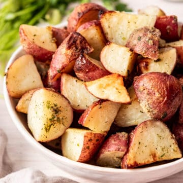 Roasted red potatoes with ranch seasoning in a white bowl.