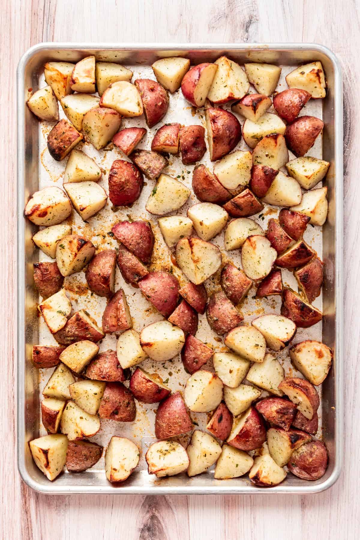 Quartered red potatoes roasted on a baking sheet.