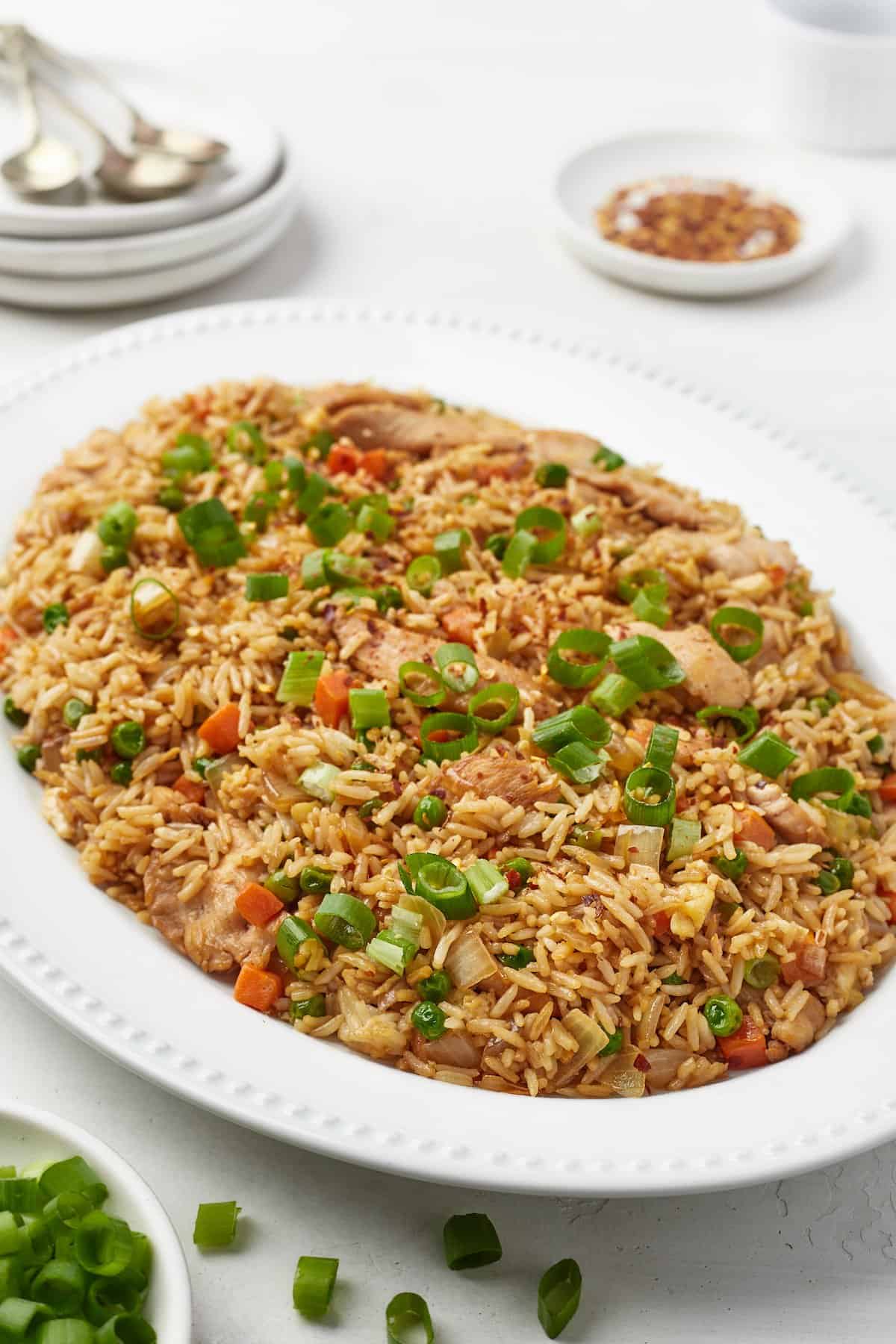 A close-up shot of chicken fried rice on a serving platter with chopped green onions on top.