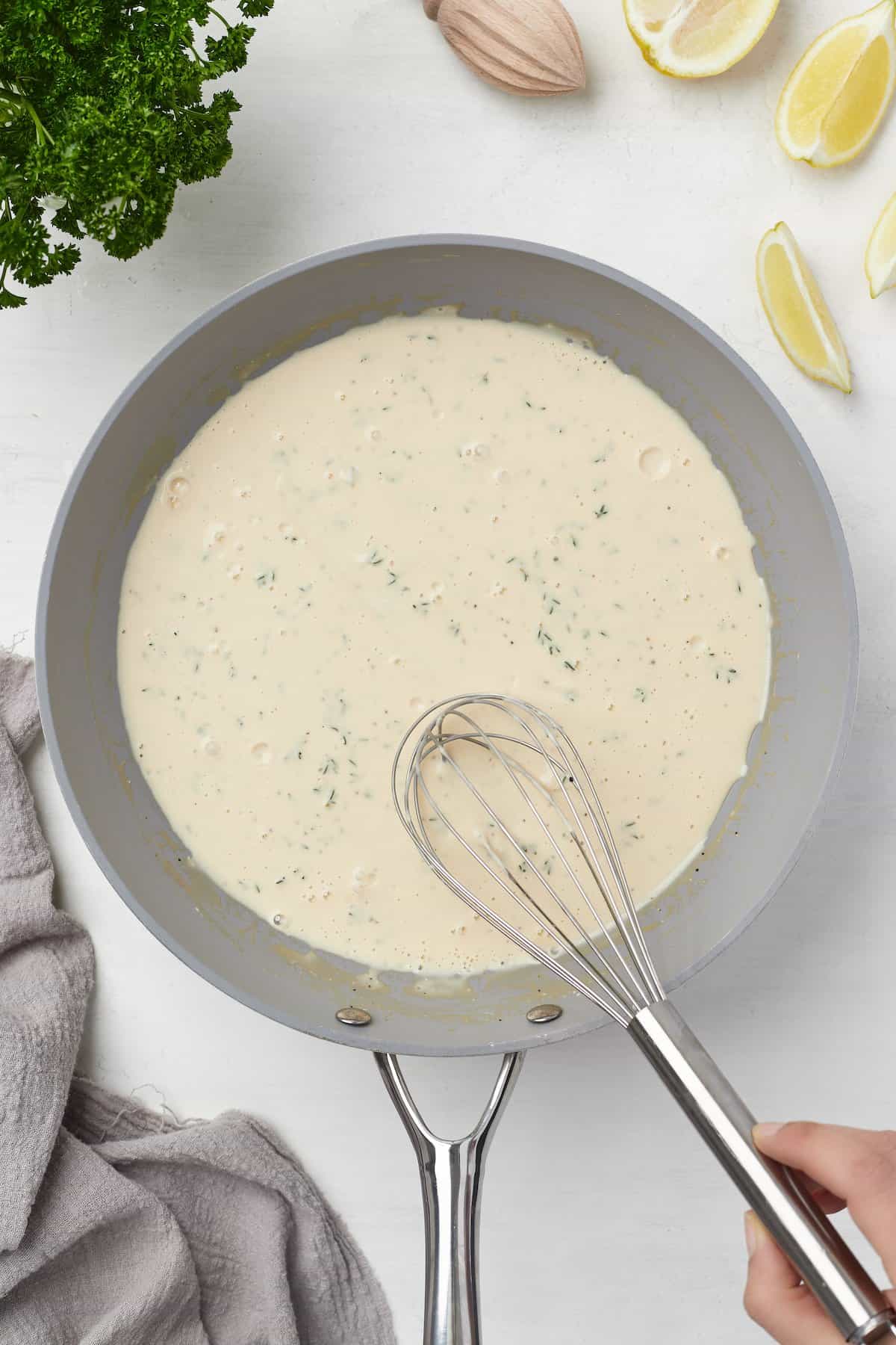 The cream cheese sauce in a skillet with a metal whisk stirring it around