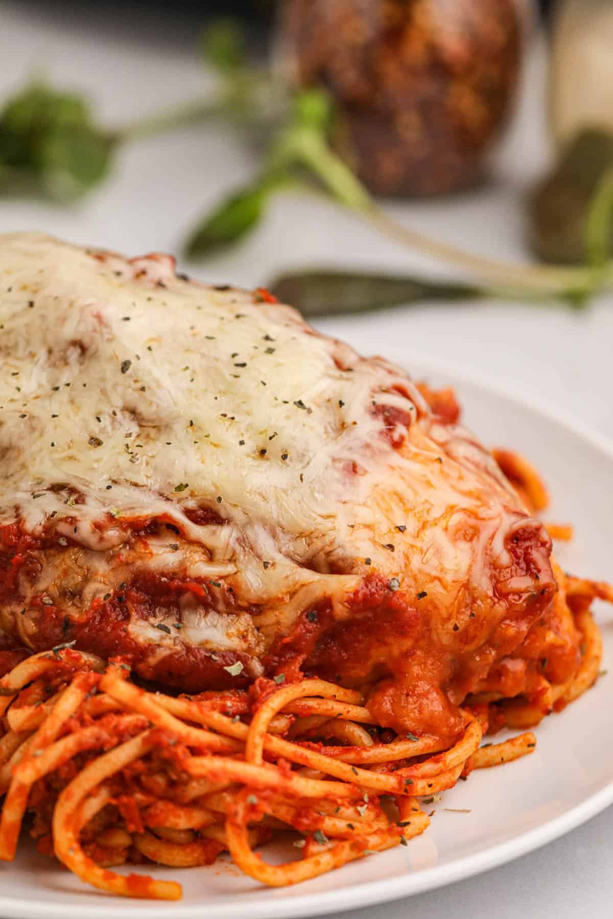 A plate of chicken parmesan over spaghetti.