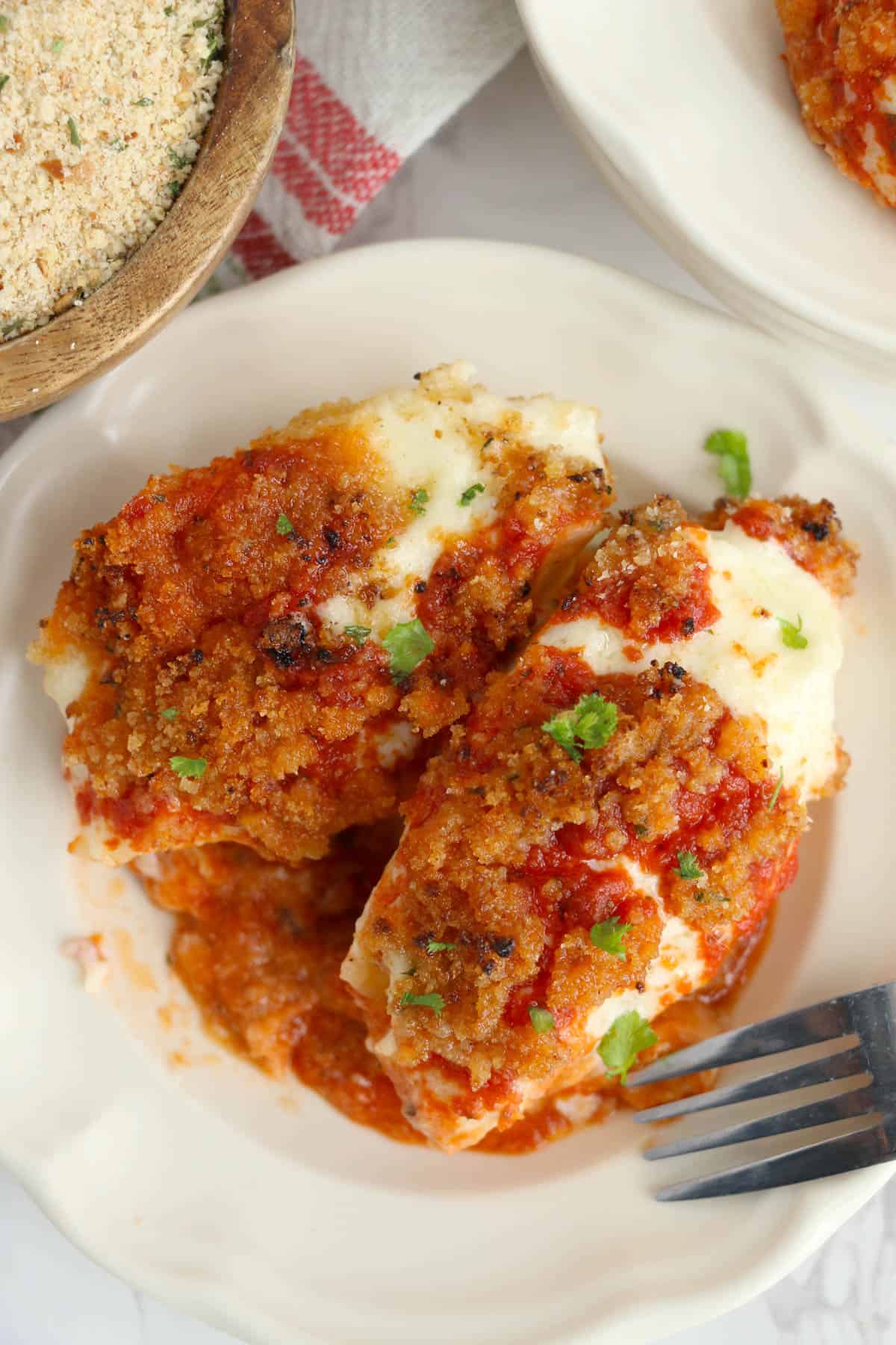 An overheat image of stuffed pasta shells with cheese, breadcrumb topping, and marinara sauce.