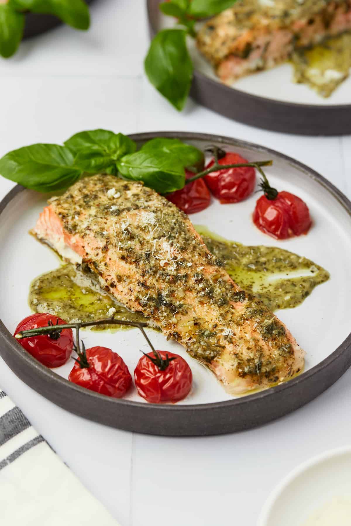 Baked pesto salmon fillet on plate with roasted tomatoes