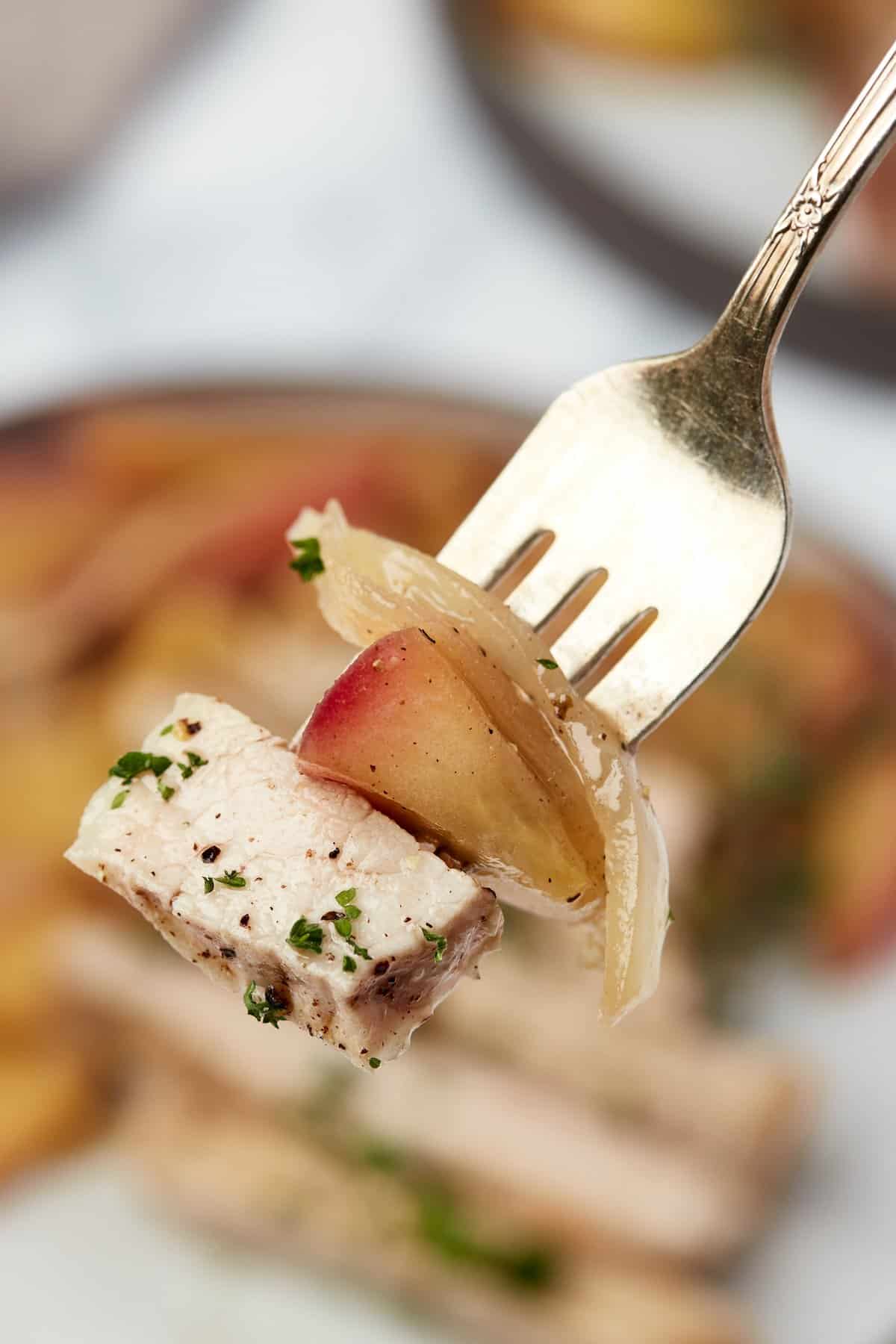 Closeup of pork chops with apples and onions on fork
