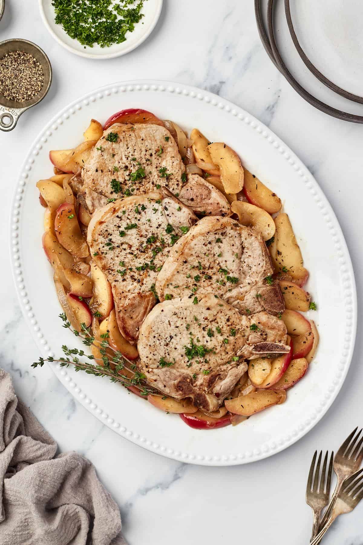 Overhead view of pork chops with apples and onions on serving platter