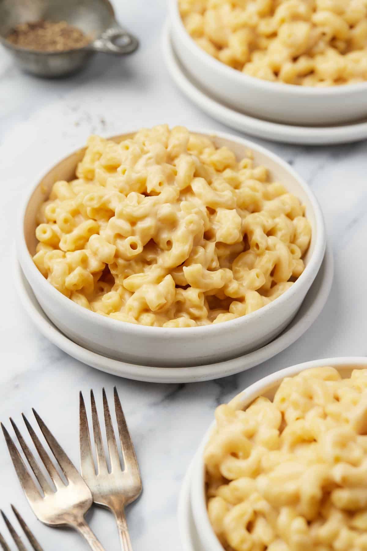 Three bowls of stovetop mac and cheese with forks nearby