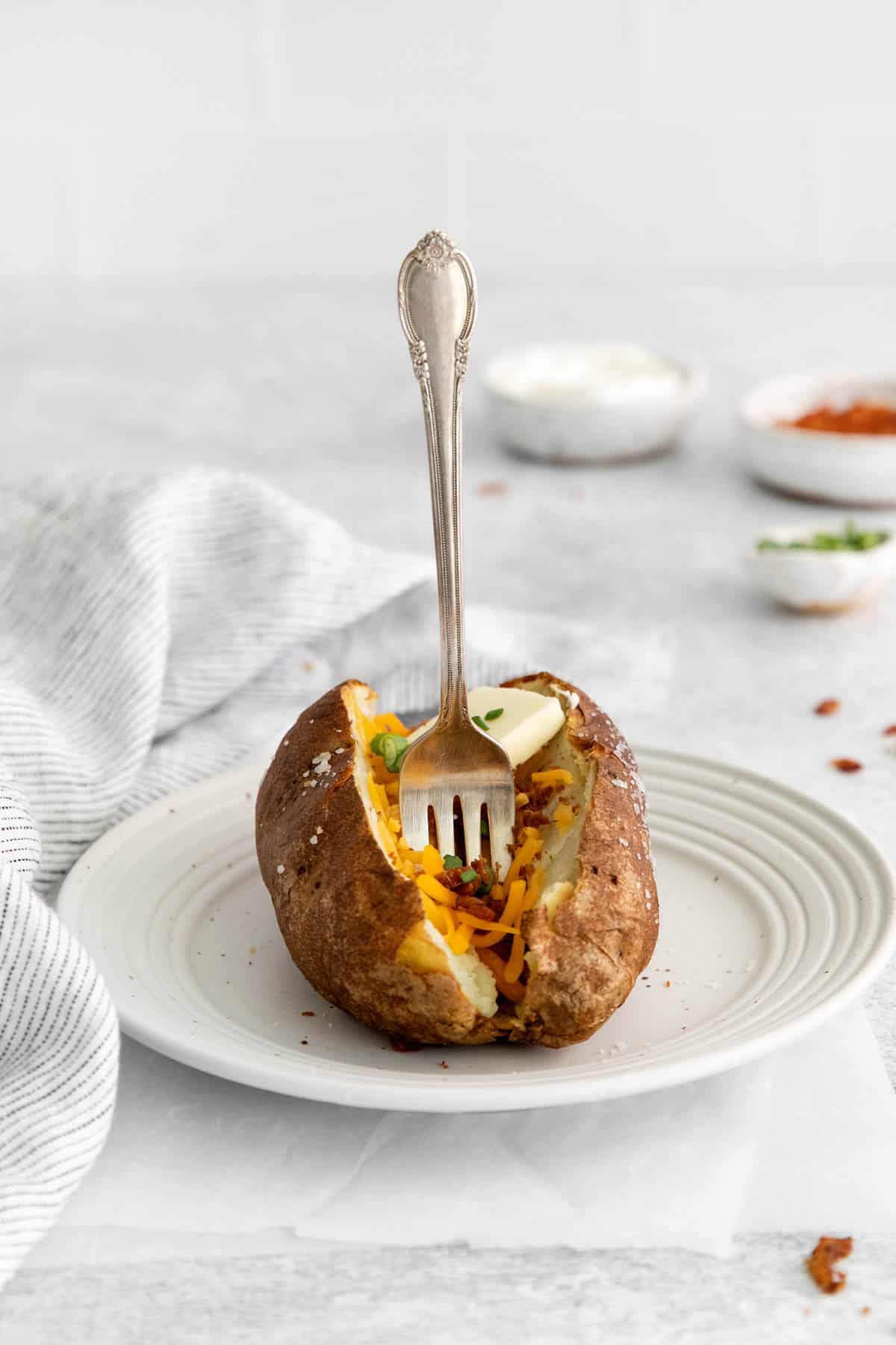 An air fryer baked potato with a fork sticking out of it.