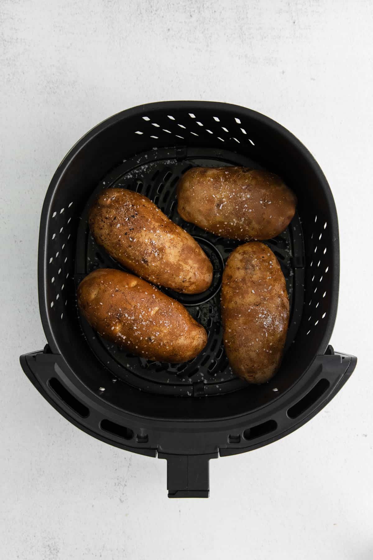 Four russett potatoes in the air fryer before baking.