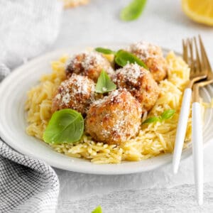 Air fryer lemon chicken meatballs on a plate with orzo pasta.