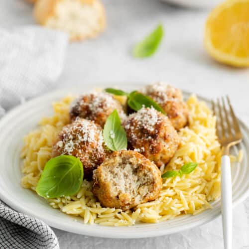 A plate of air fryer lemon chicken meatballs with a bite taken out of one of them.
