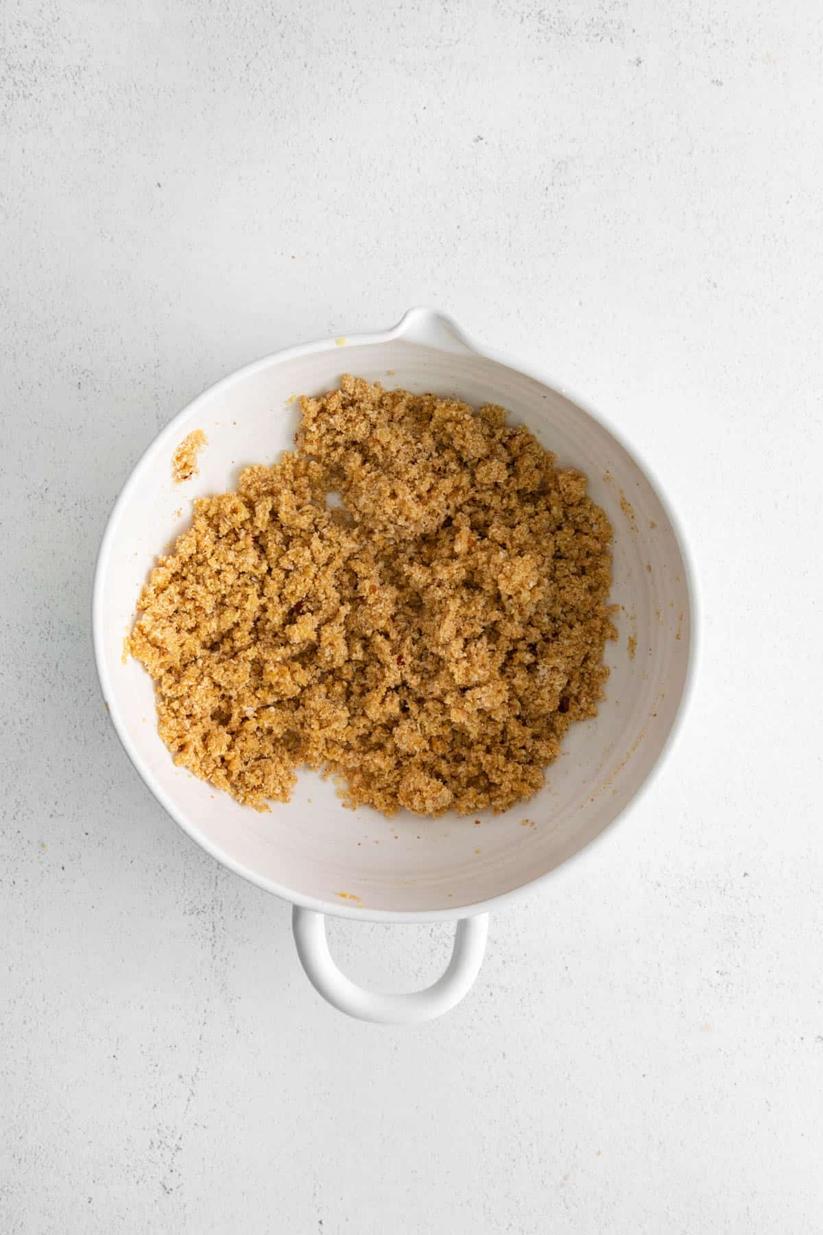 Seasoned breadcrumb mixture in a white mixing bowl.