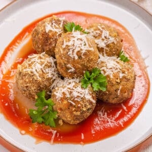 A plate of mozzarella stuffed Italian meatballs on tomato sauce.