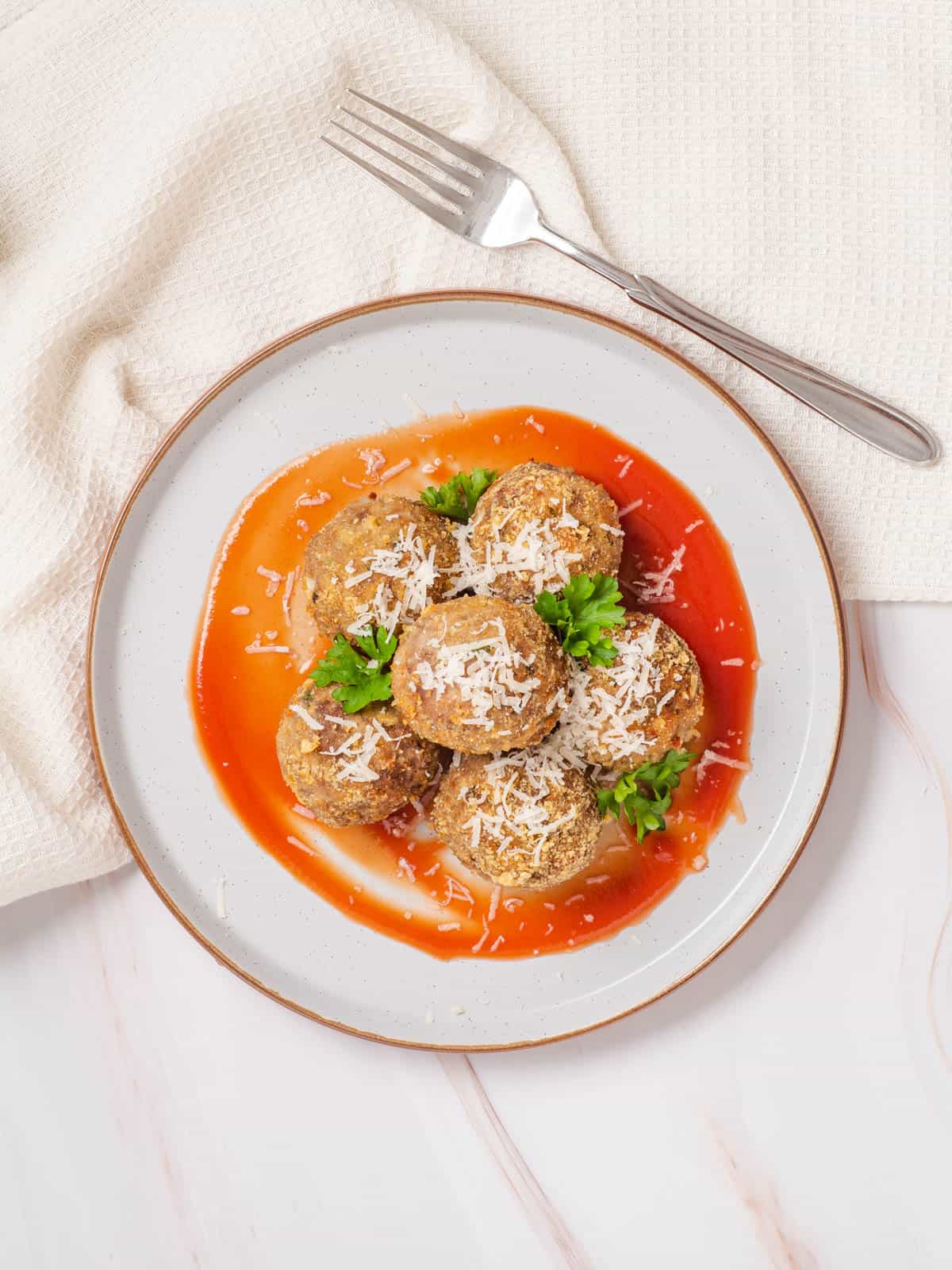 A plate with marinara sauce and air fryer meatballs.