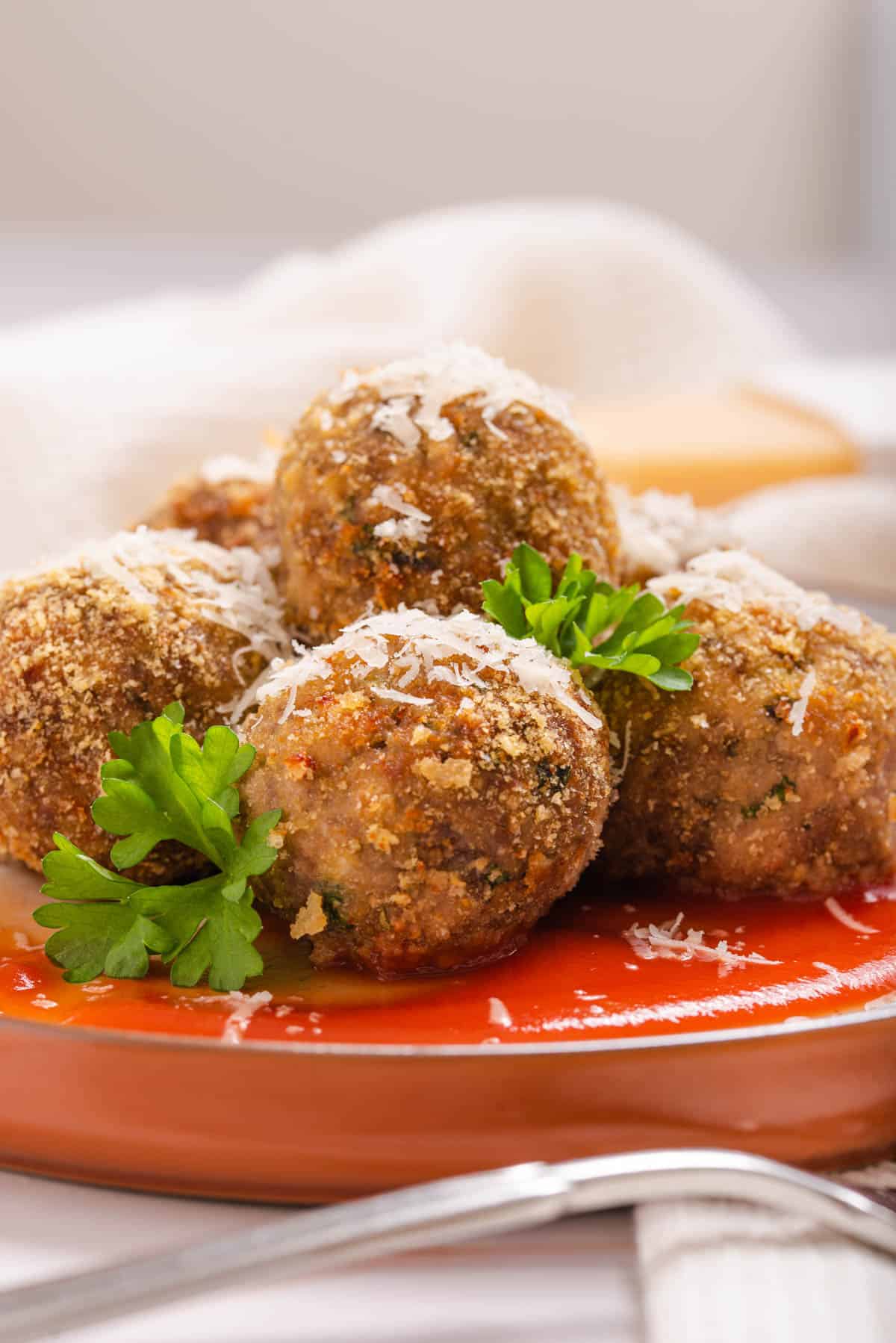 A pile of homemade meatballs stuffed with cheese on a plate with tomato sauce.
