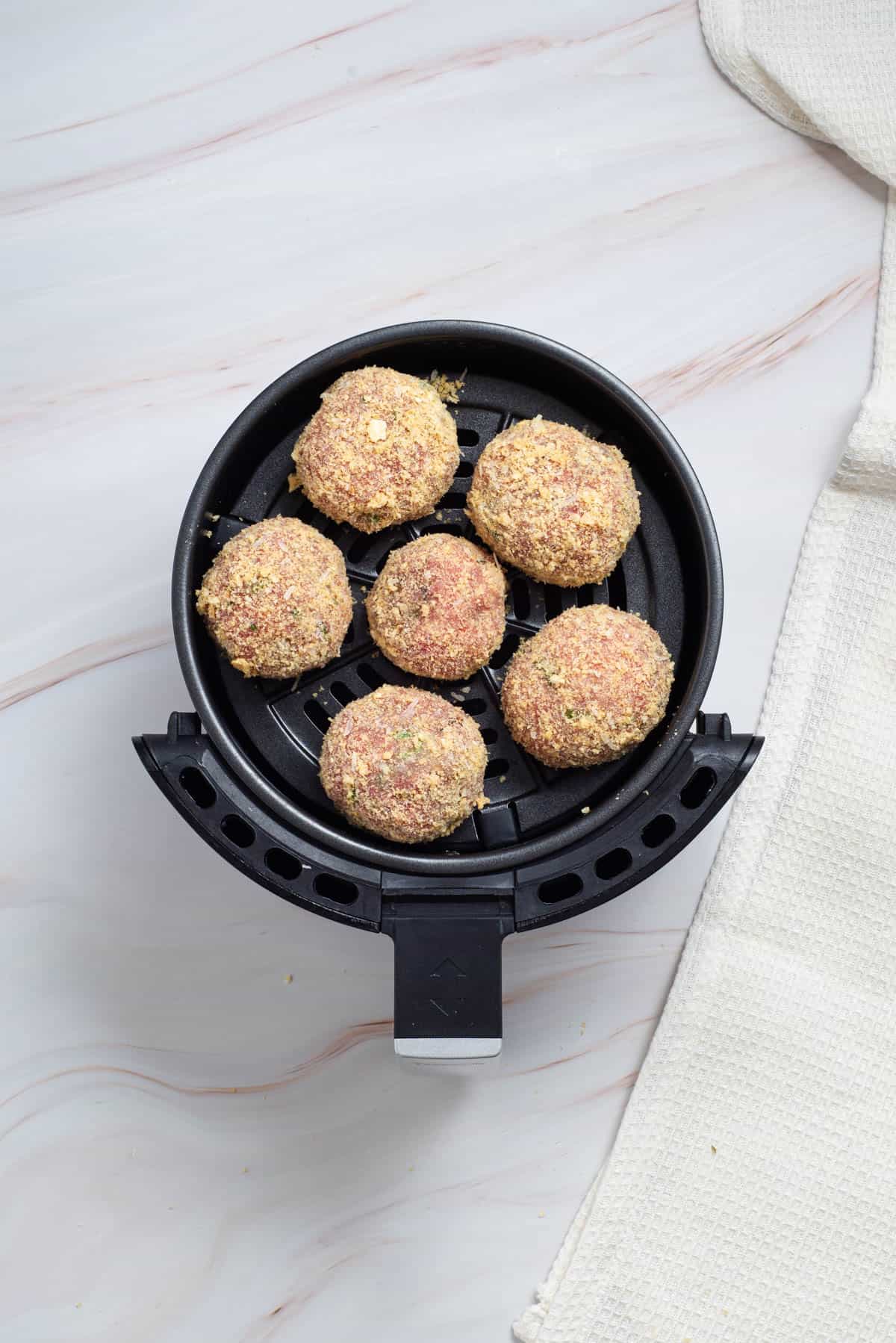 Six large meatballs in an air fryer.