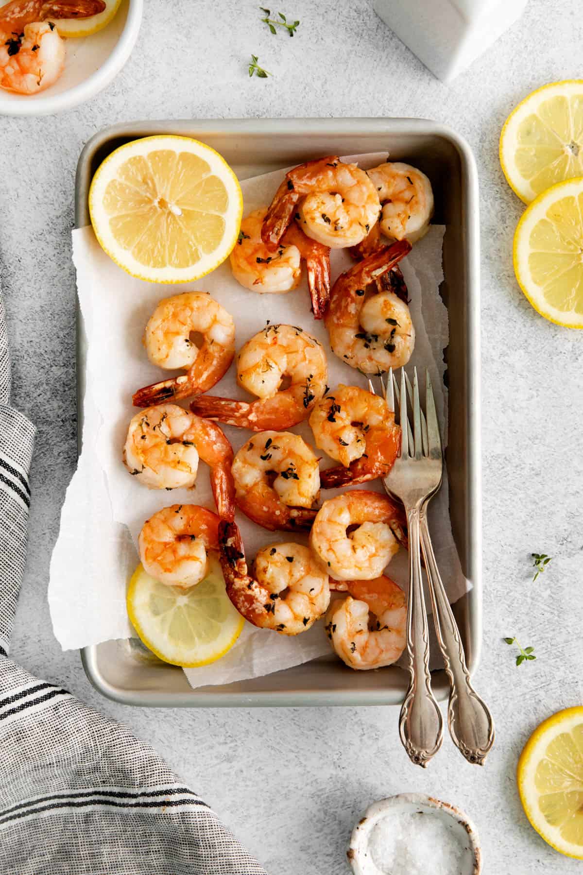 Cooked shrimp on a baking sheet with forks.