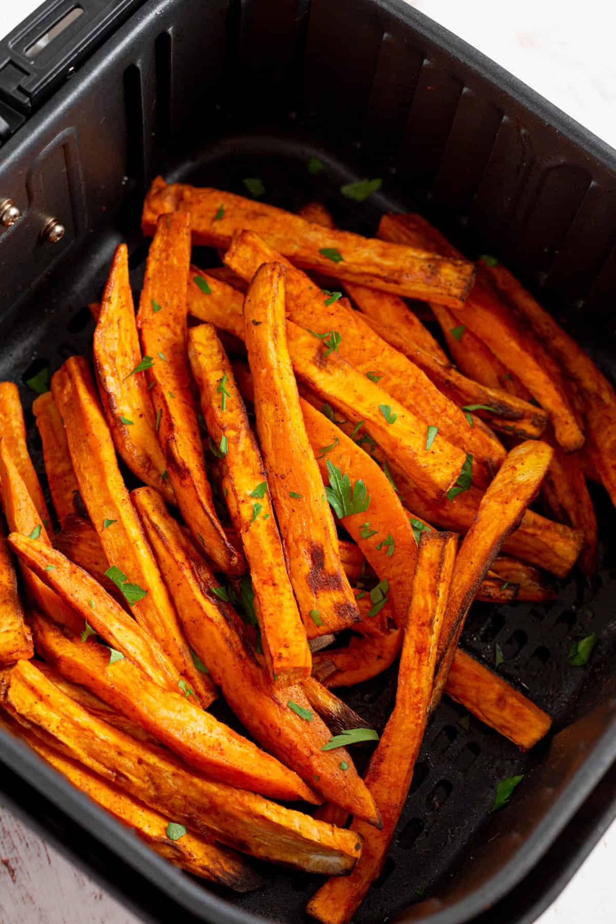 Close up overhead view of sweet potato fries in an air cooker. 