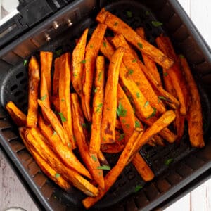 An air fryer basket filled with sweet potato fries.