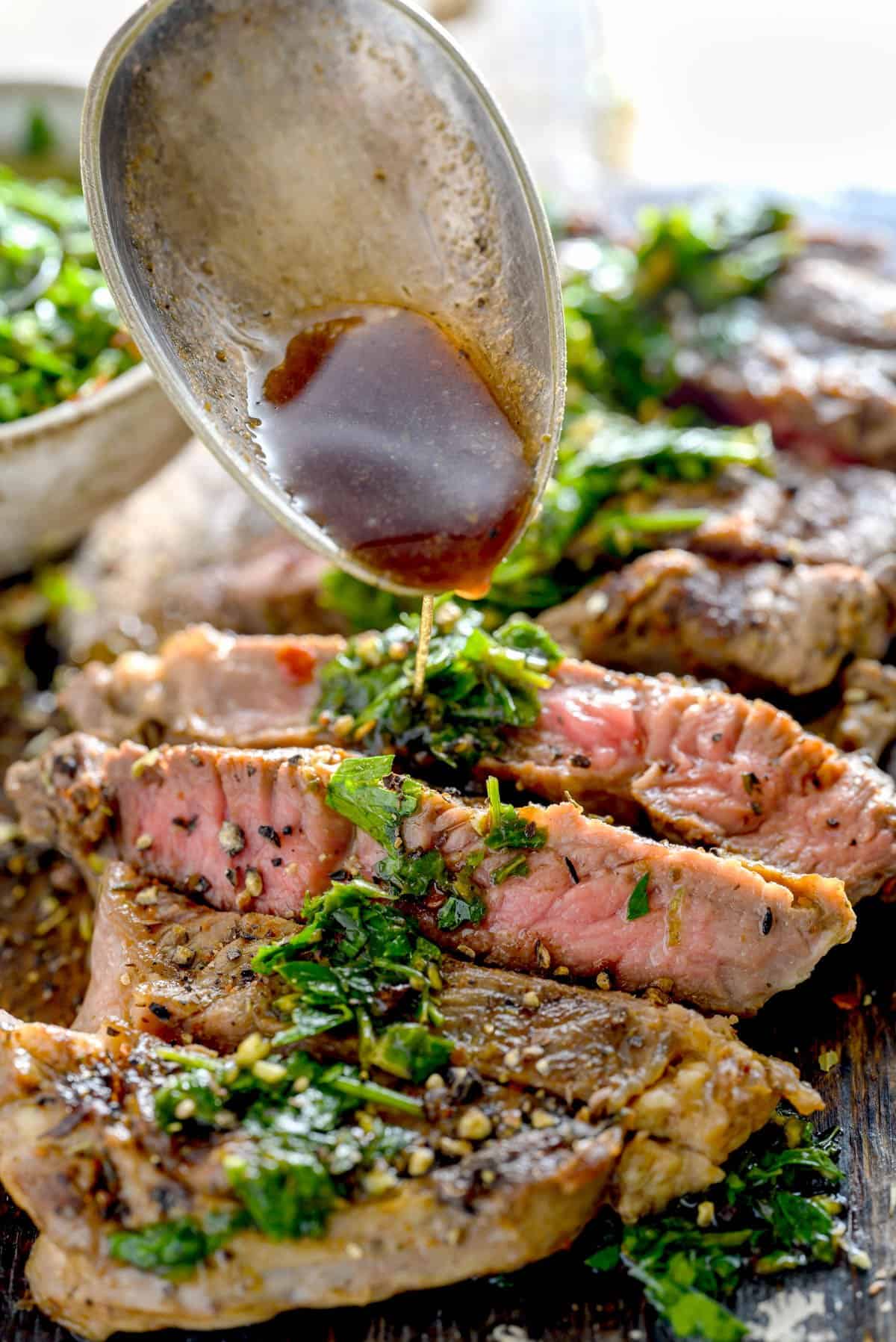 Drizzling chimichurri sauce over a cooked ribeye steak.