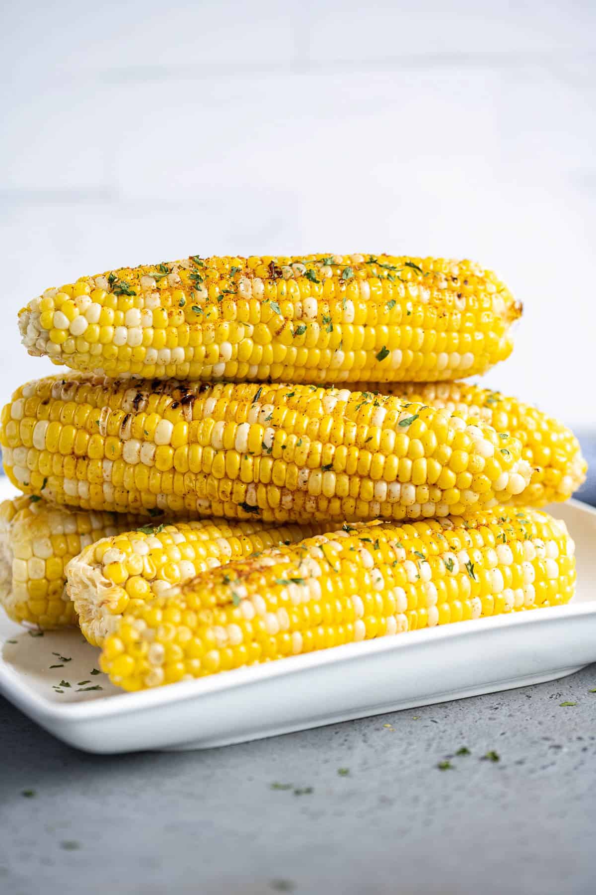 Stacked corn on the cob on a white plate.