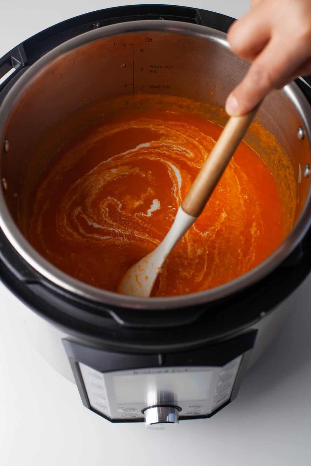 Stirring cream into tomato soup in the Instant Pot.