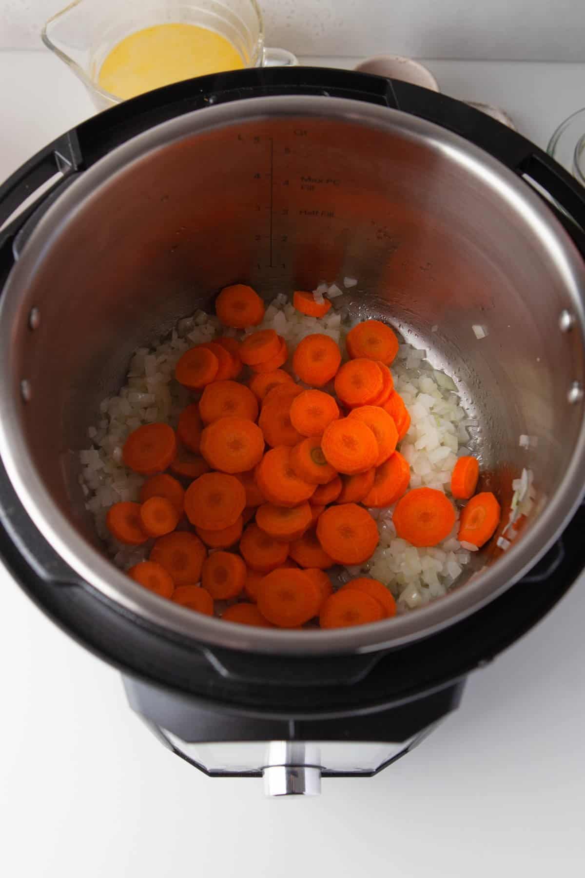 Adding carrots to sauteed onions in an Instant Pot.