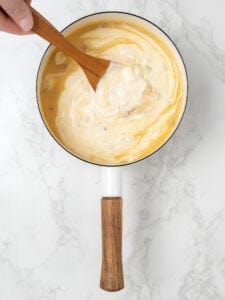 Stirring sour cream into chicken broth in saucepan