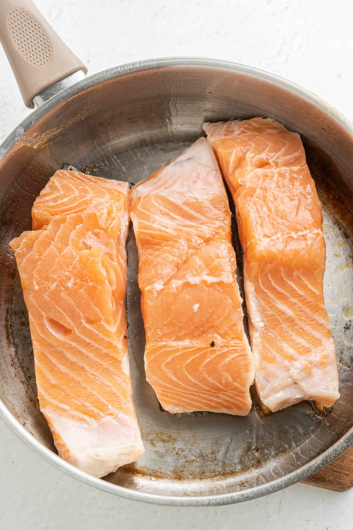 Searing salmon fillets in a large pan.