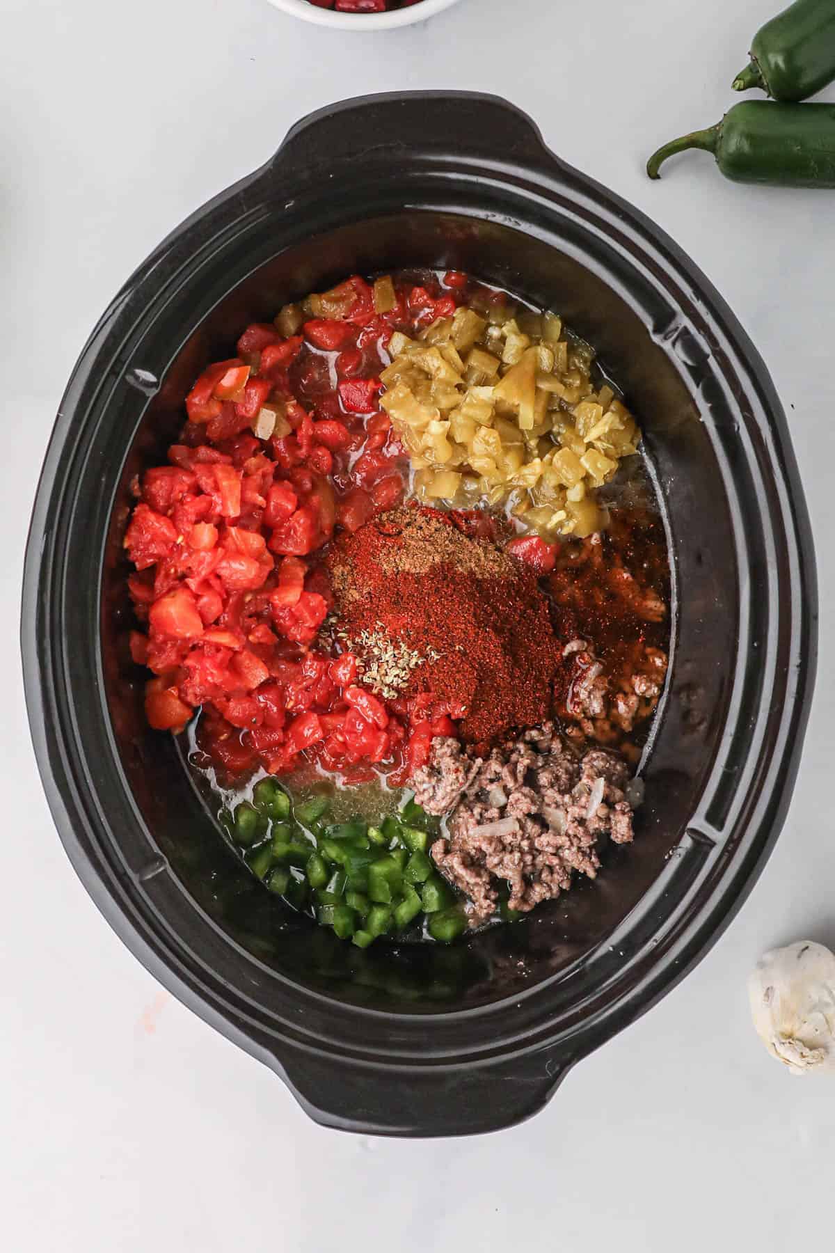 Taco soup ingredients added to a black crockpot.