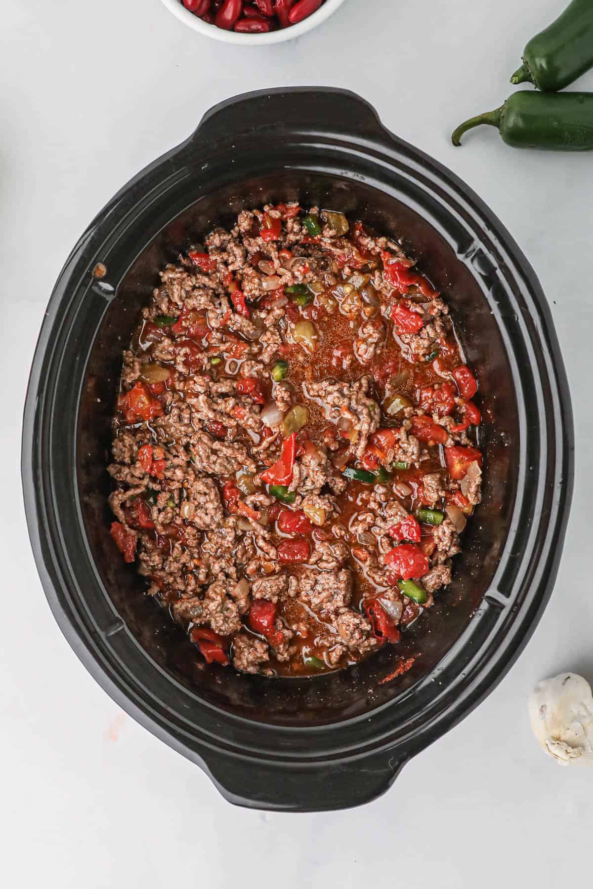 Browned ground beef and tomatoes in a slow cooker.
