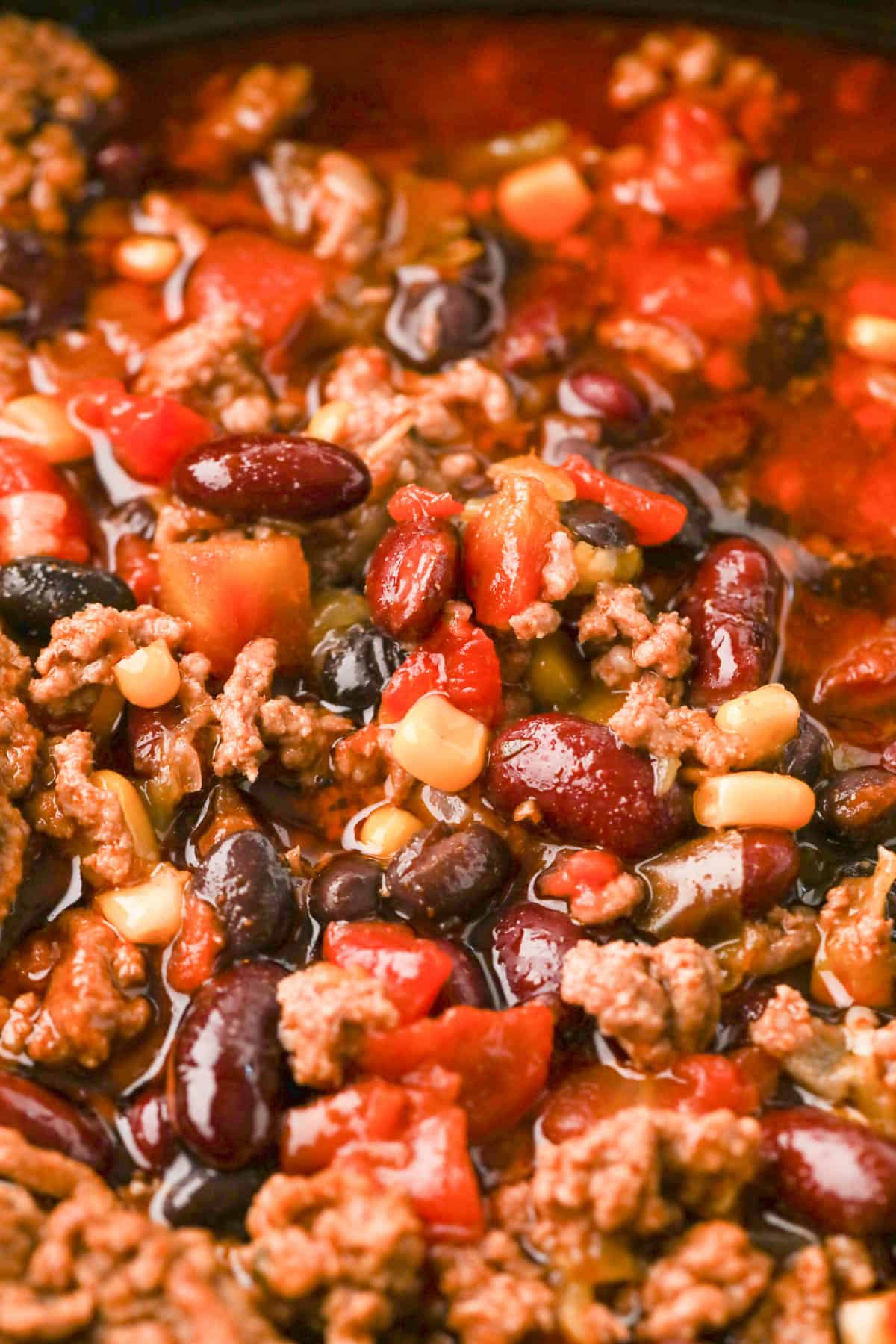 A close image of taco soup with ground beef, corn, tomatoes, and beans.